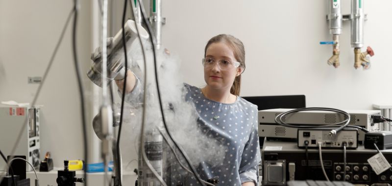 Alison Goldingay is pictured in a laboratory wearing protective goggles and performing an experiment involving a cannister of liquid nitrogen.