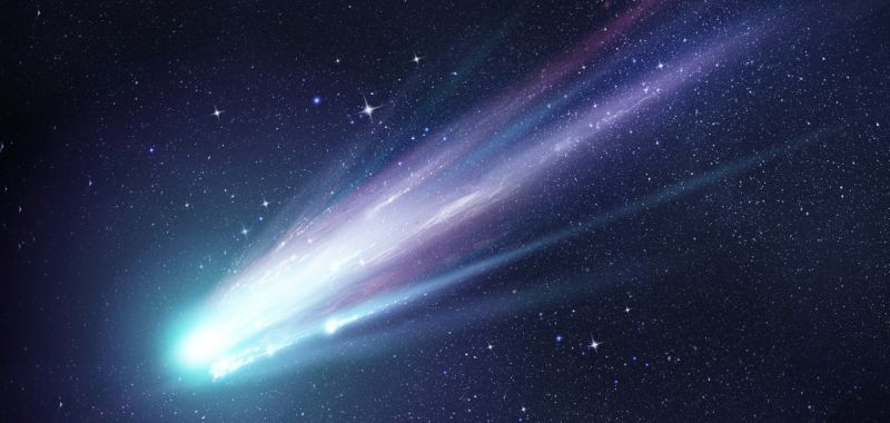An image of a comet with a green head and purple tail in space