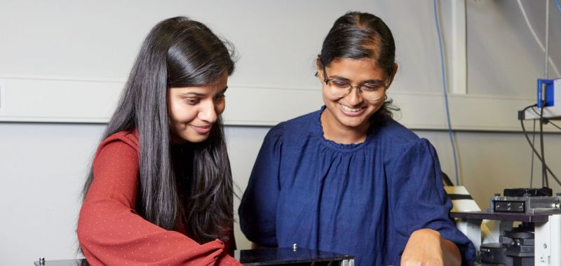 Elizabeth Thomas (right) standing with Anchal Yadav (left) in a laboratory at Monash University