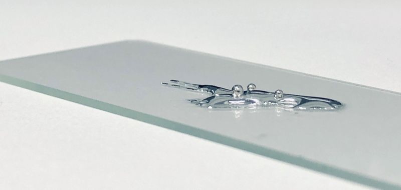 Silver-coloured liquid gallium and liquid platinum pictured in close up on a microscope slide.