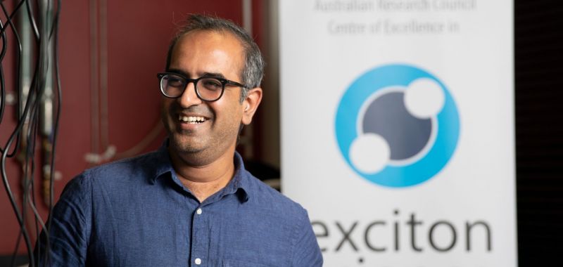 Girish Lakhwani is pictured smiling next to an Exciton Science banner 