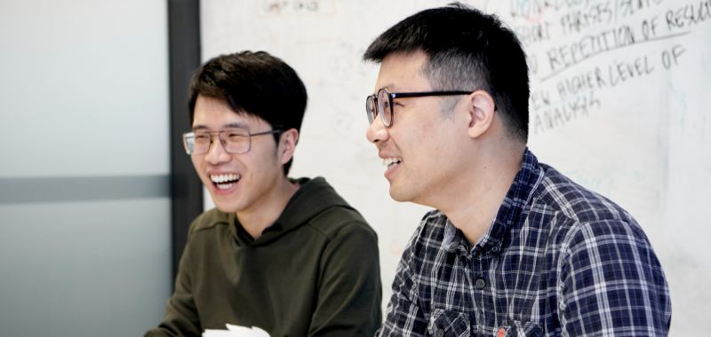 Two members of Exciton Science laughing during a conversation at Monash University