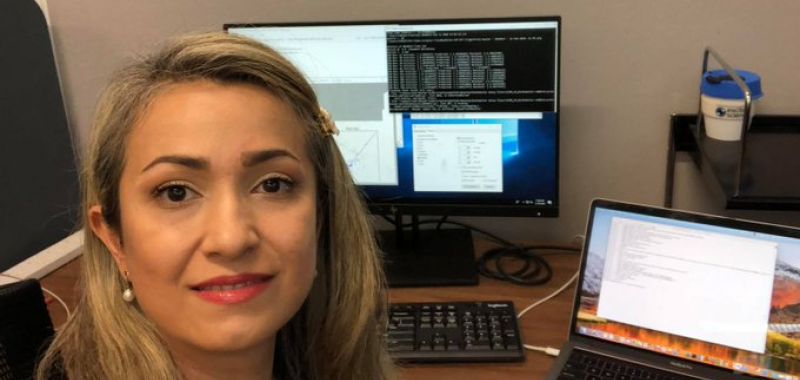 Dr Nastaran Meftahi is pictured in a selfie facing the camera and working with a computers in a home office 