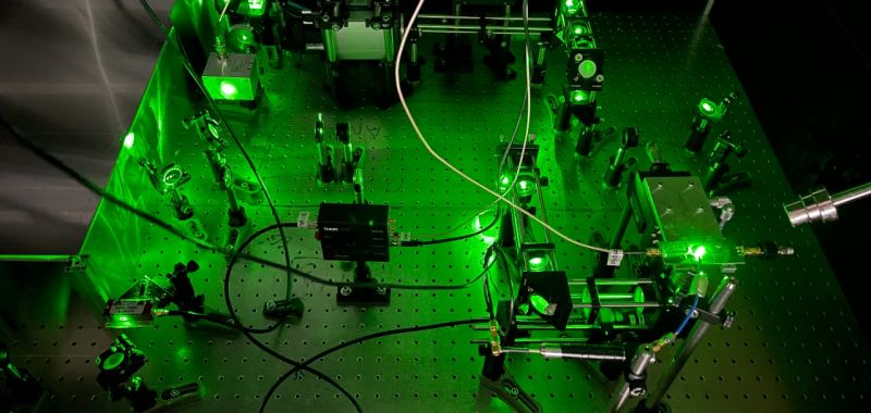 Green lasers are visible on a metal table during a science experiment