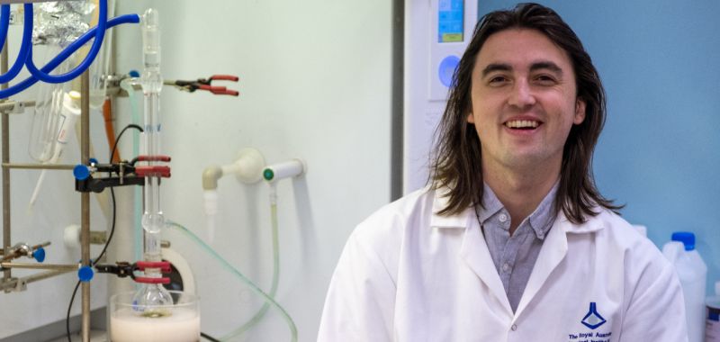 PhD student Michael Wilms standing facing the camera wearing a white lab coat at RMIT University