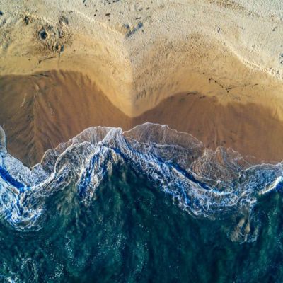 An aerial image showing ocean waves crashing onto a beach