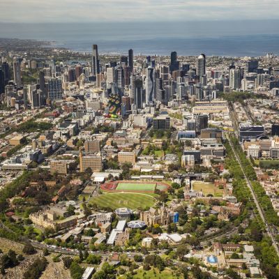 An aerial photograph of the University of Melbourne's Parkville campus, with Melbourne's CBD and Port Phillip Bay in the background