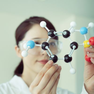 A scientist in a white coat holds up a model of a chemical structure
