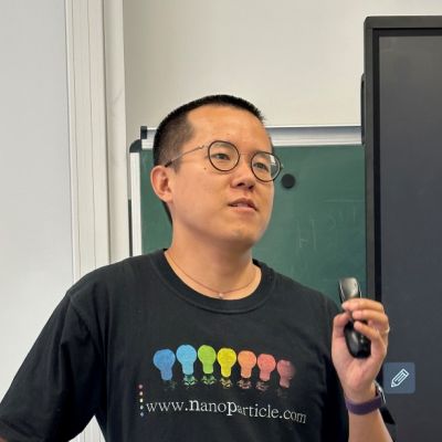 Heyou Zhang is wearing glasses and a black t-shirt during a presentation