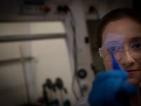 Exciton Science PhD student Alison Campbell holding a thin film in a lab