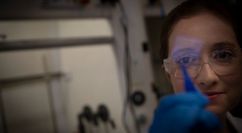 Exciton Science PhD student Alison Campbell holding a thin film in a lab