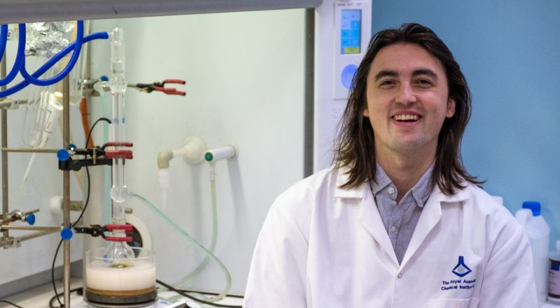 PhD student Michael Wilms standing facing the camera wearing a white lab coat at RMIT University